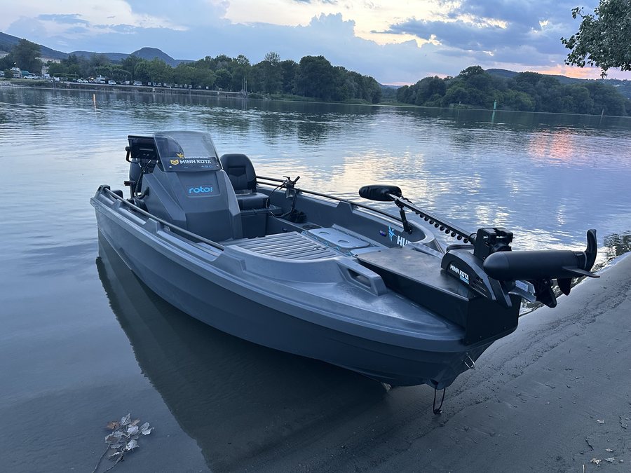 Hydra 450 rigged for fishing with a bow trolling motor and sonar, drawn up on a river bank